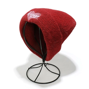 Detalle de gorro de punto burdeos con corazón bordado y texto Be Happy en tela suave