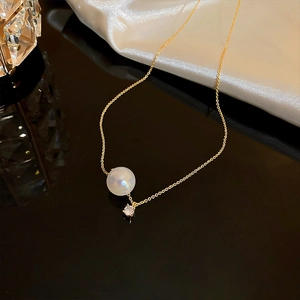 Detail of elegant gold stainless steel necklace with pearl and sparkling zircon pendant
