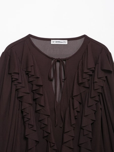 Detailansicht des Ausschnitts mit Bändern und Markenetikett am braunen Langarmkleid