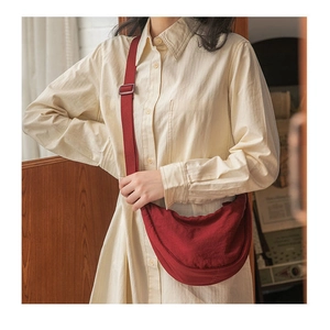 Detail of red canvas crescent bag with adjustable strap worn by model in casual style