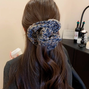 Détail d'un chouchou en maille à carreaux bleu-gris porté dans une ambiance d'automne