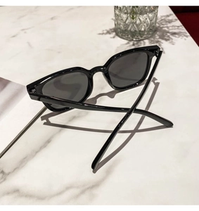 Close-up of stylish black square sunglasses with dark UV lenses on marble surface