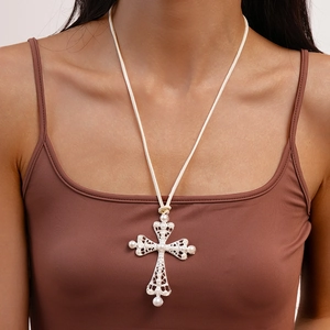 Macro shot of large silver hollow cross pendant with faux pearl inlays on a cord necklace