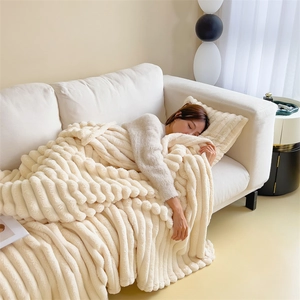 Soft cream faux rabbit fur throw blanket with luxury textured stripes on a cozy sofa