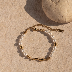 Close-up of 18k gold-plated stainless steel pearl bracelet with wavy pendant