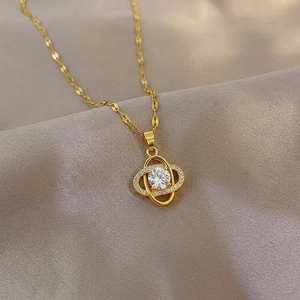 Elegant gold titanium steel clover necklace with sparkling cubic zirconia on silk background