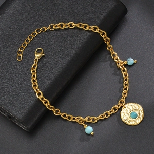 Detail of gold chain bracelet with turquoise beads and hammered evil eye pendant