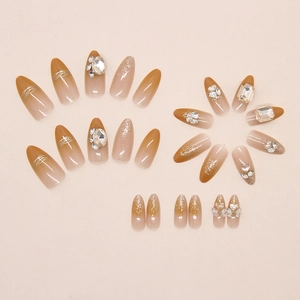Macro detail of almond press-on nails with brown gradient, glitter, and rhinestone accents