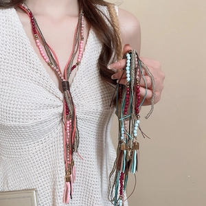 Close-up of bohemian layered beaded necklace with leather tassels and woven rope detail
