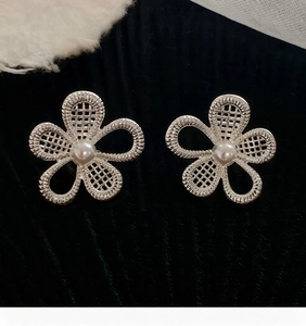 Detailed macro view of silver hollow floral stud earrings with pearl center in high quality