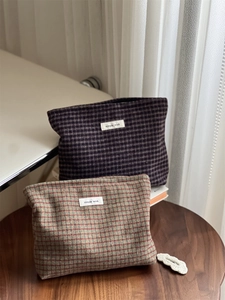 Detail view of vintage plaid wool makeup bags in purple and brown on a wooden table