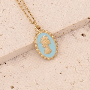 Detail of a gold cameo necklace with blue enamel pendant on a natural stone surface