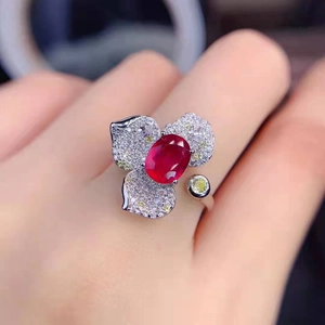 Detailed close-up of a flower-shaped ring with a red gemstone and micro-pave diamonds