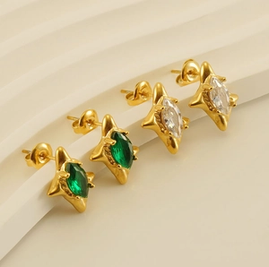 Macro detail of 18k gold plated star earrings with green and white marquise zircon stones