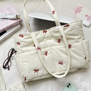 Detail of quilted tote bag with red bow embroidery featuring large capacity and soft texture