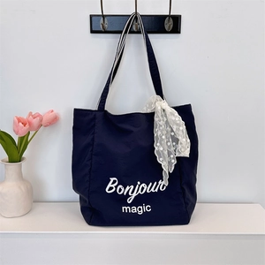 Detail of blue canvas tote bag with Bonjour magic print and lace ribbon handle