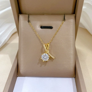 Détail du pendentif ruban croisé avec grand zircon rond et chaîne dorée élégante