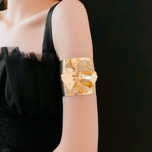 Detailed view of wide gold metal upper arm cuff with large 3D flower design