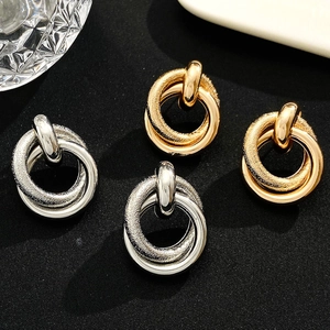 Exaggerated geometric intertwined hoop earrings in gold and silver matte metal finish