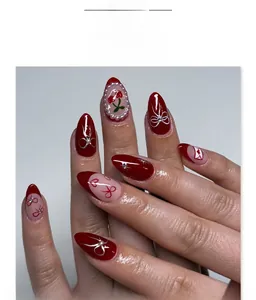Detail of almond-shaped press-on nails with red bows, cherry art, and pearls