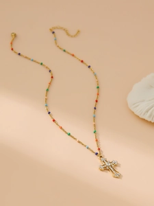 Detail of gold beaded chain necklace with multi-colored stones and rhinestone cross pendant
