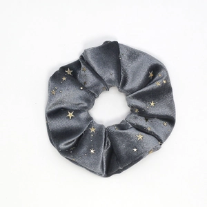 Dark grey velvet scrunchie with gold star pattern prints on a clean white background