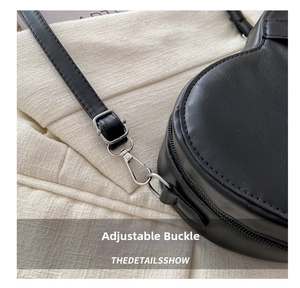 Détail de la bandoulière réglable et de la boucle en métal argenté sur sac noir en cuir