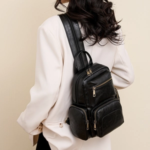 Rear view of a black faux leather backpack on a model showing size and styling