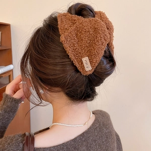 Detail van bruine pluche haarklem met berenlabel op een knotje bij een vrouw