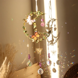 Moon-shaped suncatcher with purple crystals and metal leaves creating rainbow light spots