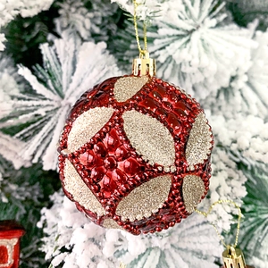 Detail einer rot-goldenen Weihnachtskugel mit geometrischem Rautenmuster und Glitzer am Baum