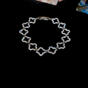 Close-up of silver four-leaf clover bracelet with sparkling pavé zircons on black background
