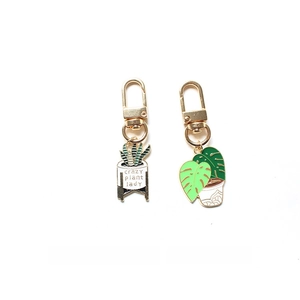 Close-up of Crazy Plant Lady keychain charms with enamel leaf and potted plant designs