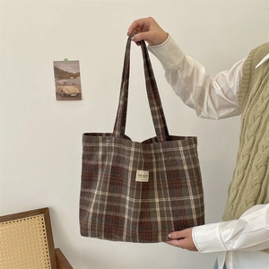 Detailed close-up of brown vintage plaid tote bag with stitched fabric logo label