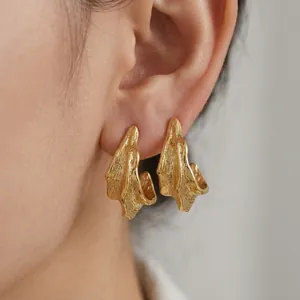 Detailed macro view of gold irregular wavy earrings with a textured brushed metal finish