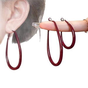 Retro deep red oval hoop earrings with glossy finish shown on model and hand