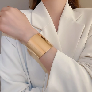 Close-up of wide gold cuff bracelet featuring a mirror-finish and stylish crinkled design