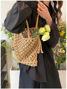 Detail view of a beige handmade woven mesh bag held by a model for vacation styling