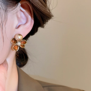 Close-up of 18k gold plated flower stud earring with brown resin and pearl on model