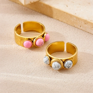 Detail of 18k gold plated adjustable rings with pink and turquoise stones on stone backdrop