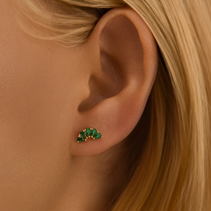 Close-up of a gold-plated flower stud earring with green emerald-cut zircon on the ear
