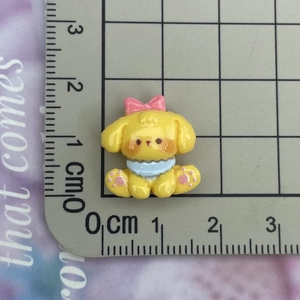 Macro view of mini yellow puppy resin charm with pink bow showing 2cm scale measurements