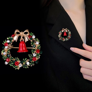 Christmas wreath brooch with gold bow and red bell shown on elegant black blazer lapel
