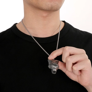 Detail shot of a men's punk style silver wolf head pendant worn on a dark shirt