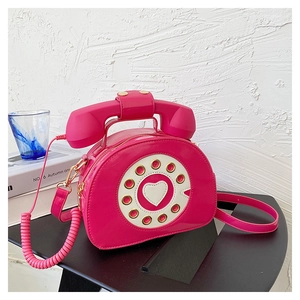 Detailed close-up of a pink telephone-shaped crossbody bag with a heart dial pattern