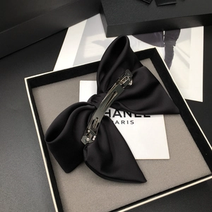 Close-up of black satin bow hair clip with silver metal spring fastener on velvet lining