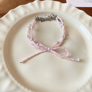 Gros plan du collier nœud perlé rose avec perles d'imitation sur assiette décorative