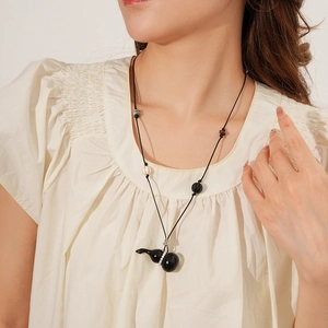Close-up of a Zen-style necklace with a wooden gourd pendant and beaded wax cord