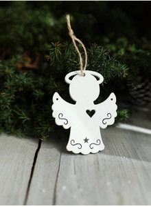Close-up of a white wooden angel ornament with heart cutouts on a pine tree branch