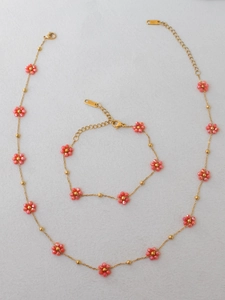 Detail of bohemian gold stainless steel jewelry set with pink beaded floral designs